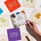 Spice-themed card game with colorful cards and a box labeled 'Spice Rainbow' on a white surface.