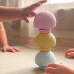 Colorful tactile sensory ball toy with a pink top, yellow middle, and blue bottom on a light surface.