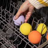Hand placing colorful easy to clean bath balls into a dishwasher