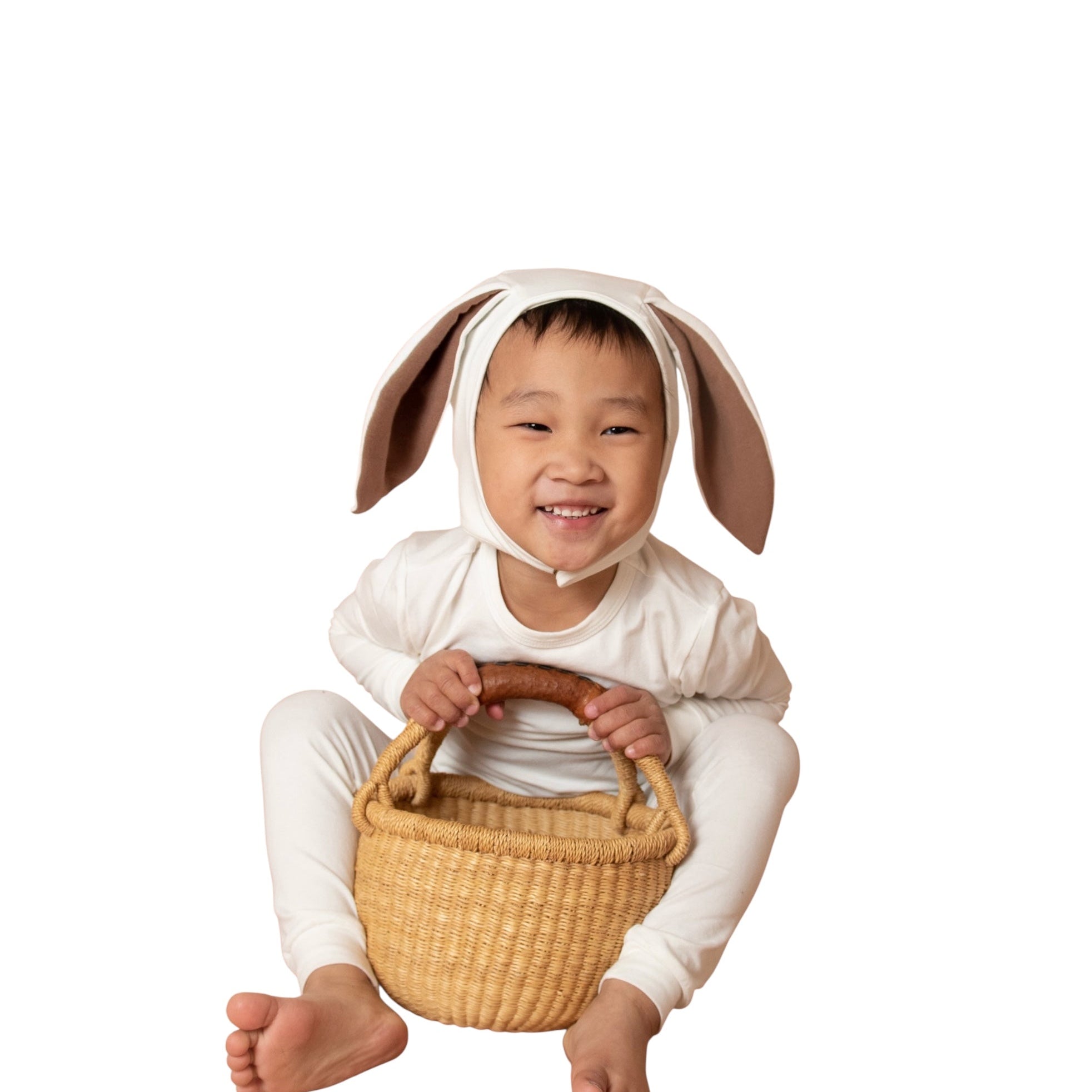 Child wearing a bunny costume with a basket on a white background
