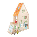 Wooden dollhouse with decorative elements and small figures on a white background